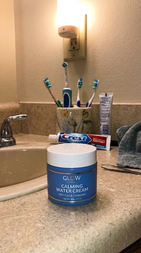 Before photo of a blue skincare water cream jar on a cluttered bathroom counter